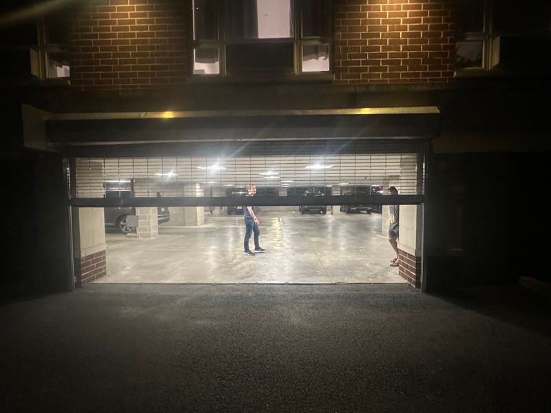 Parking garage security grille partially open at night showing garage interior