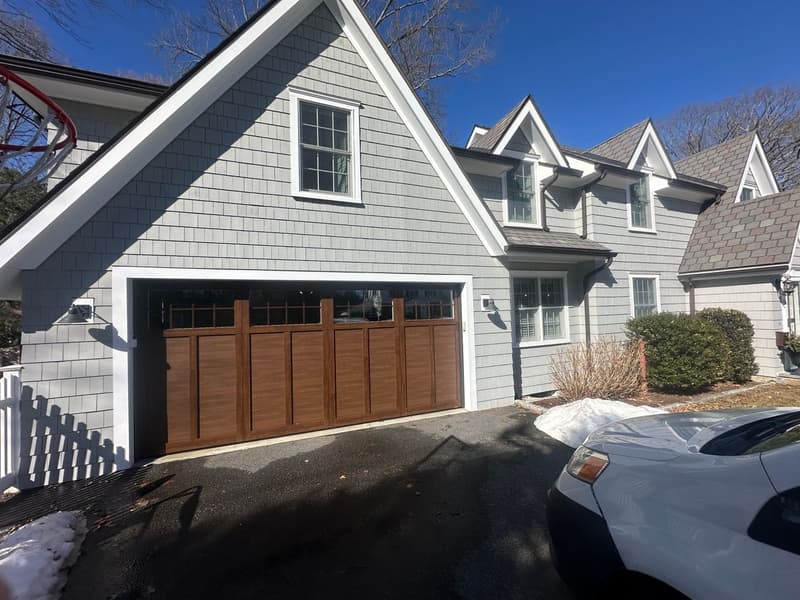 Wide angle view of wood garage door installation with snow on ground
